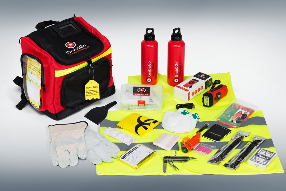 Grab bag and contents including hi-vis vest, garden gloves, pocket knife, whistl, glow sticks, rain poncho, dust mask, wind up radio/torch, scraper, foil blanket, water bottles, notebook and pen, playing cards, first aid kit