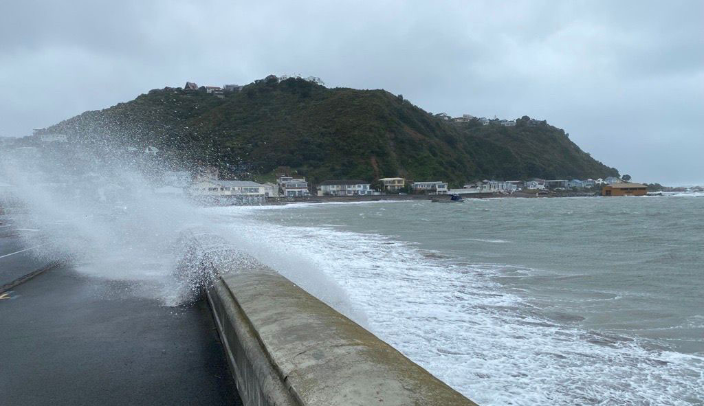 waves are overtopping a seawall in wellington and water is covering the footpath